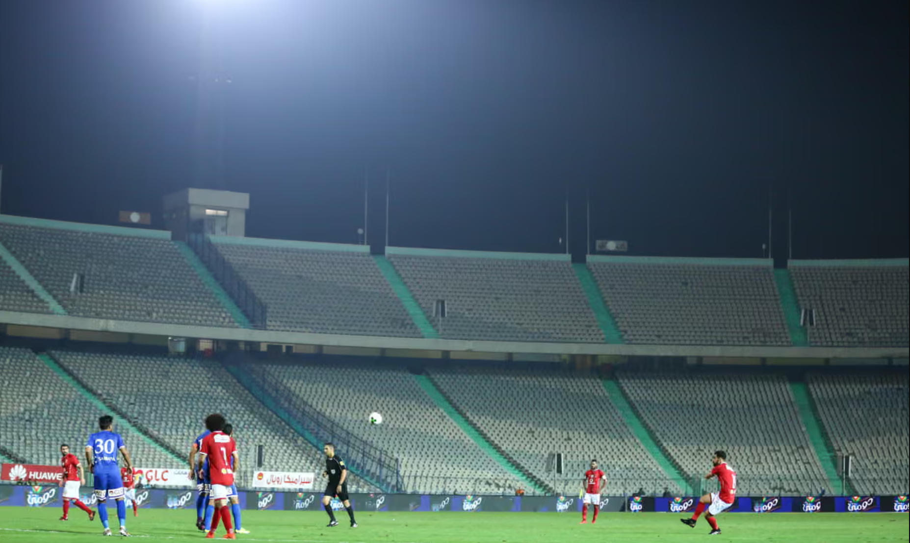 Al Ahly and Zamalek playing in a completely empty Cairo stadium under floodlights
