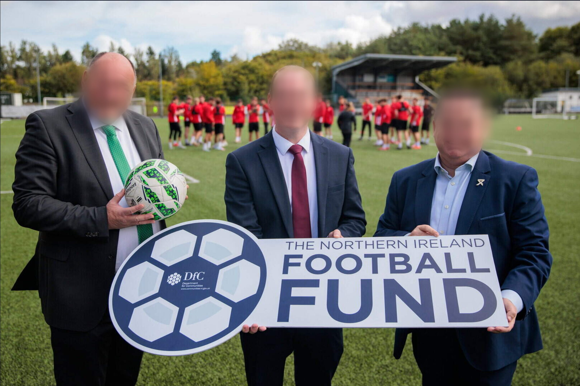 A small Irish League ground under floodlights, a covered terrace down one side